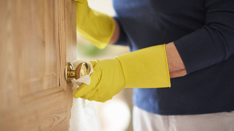 woman wiping down a doorknob