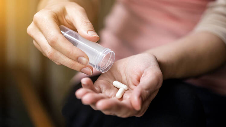 Woman with white pills in her hand