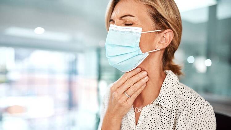 mature woman wearing a mask and touching her throat