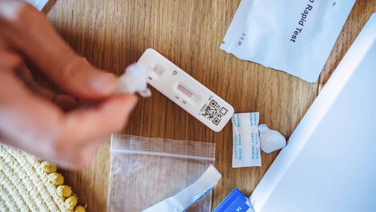 close up of free COVID-19 test on table, hand dropping liquid into test