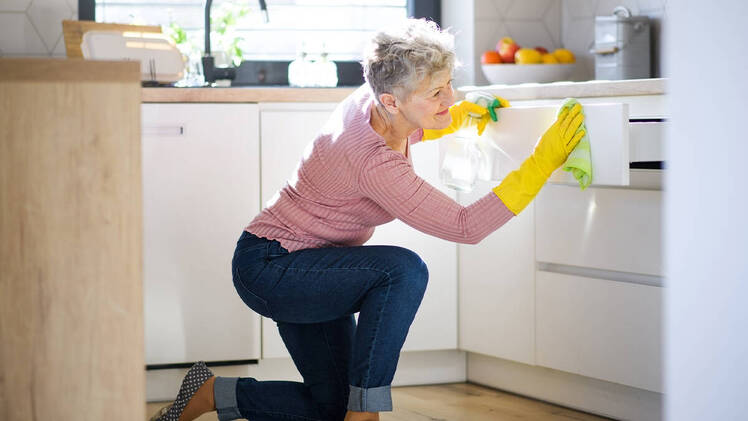 Woman cleaning a kitchen cabinet quick home cleaning tasks