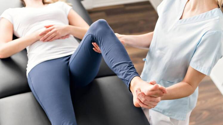Woman getting leg stretched by stretch therapist