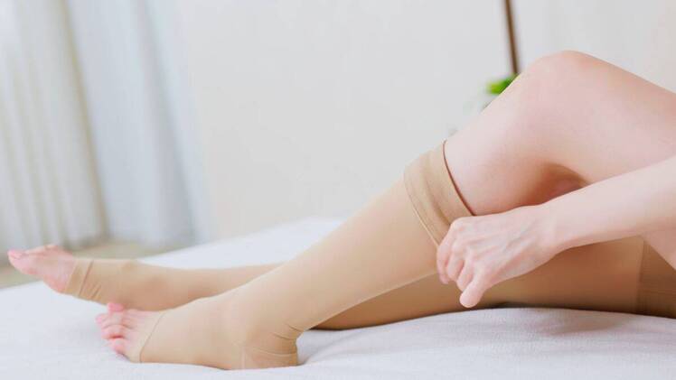 woman putting on compression socks after finding out how to get rid of swollen ankles fast