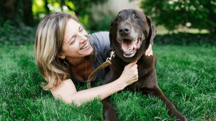 woman hugging and smiling at chocolate labrador