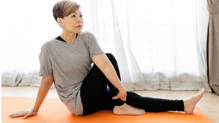 woman doing yoga for stomach pain at home seated spine twist