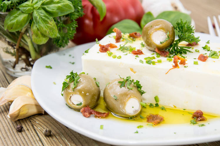 Cheese stuffed olives on top of a block of feta cheese