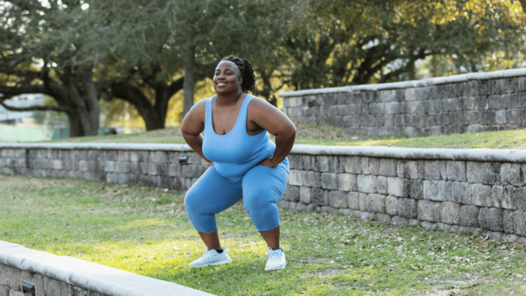 woman outdoors doing a bodyweight squat as part of metabolic conditioning exercises