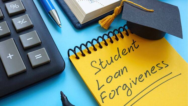 Graduation cap, pen, marker, calculator, Student Loan Forgiveness written on notepad