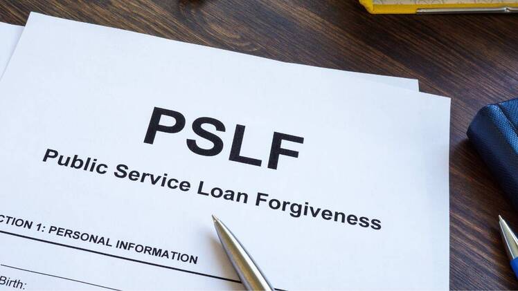 Papers for Public Service Loan Forgiveness PSLF on wooden surface.