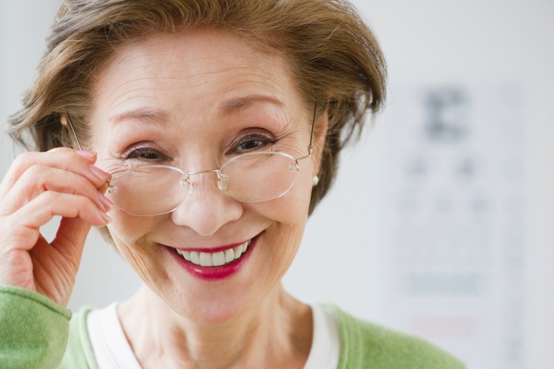 older woman holding her glasses and smiling
