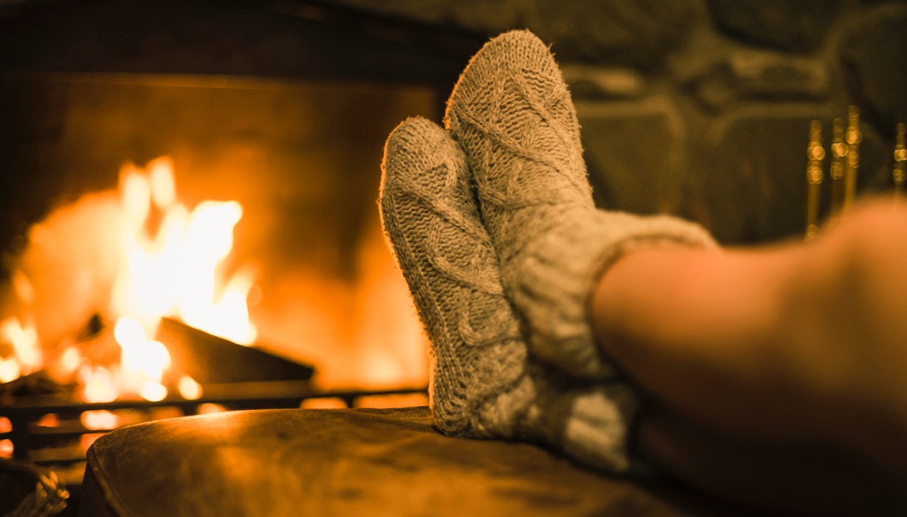 a pair of sock-clad feet propped up in front of a fireplace