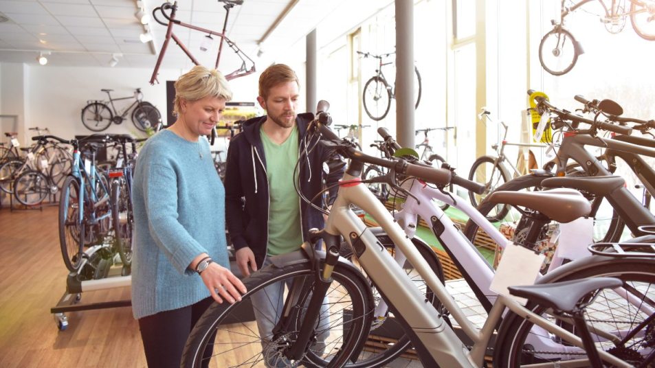 FILE--A woman rides an electric bike past a fashion boutique of