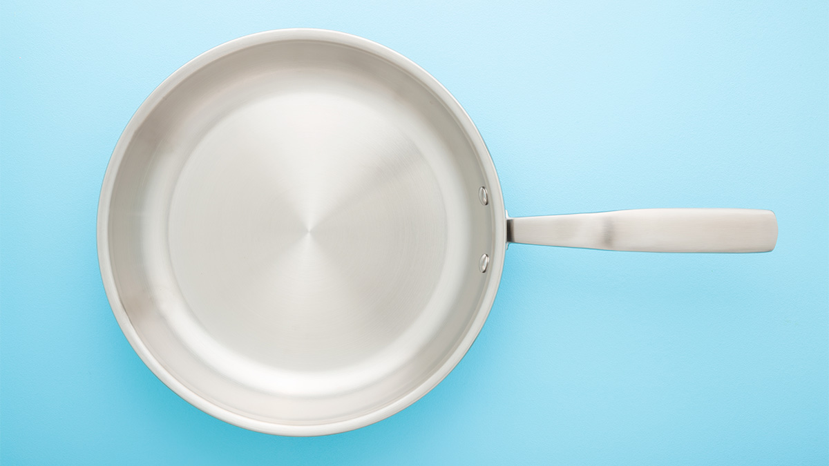 https://www.firstforwomen.com/wp-content/uploads/sites/2/2023/01/A-stainless-steel-skillet-against-a-blue-background.jpg