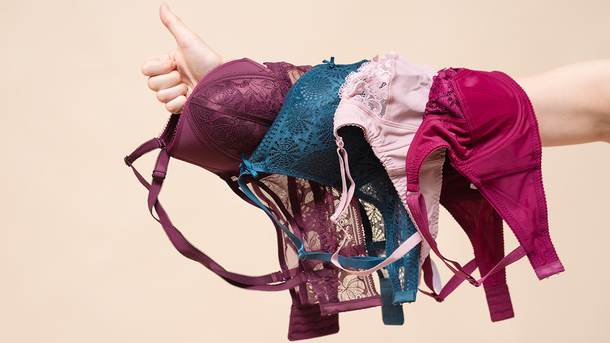https://www.firstforwomen.com/wp-content/uploads/sites/2/2024/02/Woman-with-various-bras-on-her-arm-and-a-thumbs-up-gesture.jpg