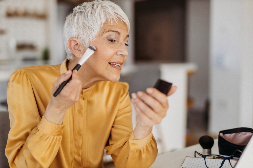 mature woman applying makeup