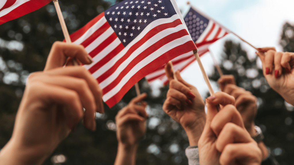 Hands holding small American flags in the air