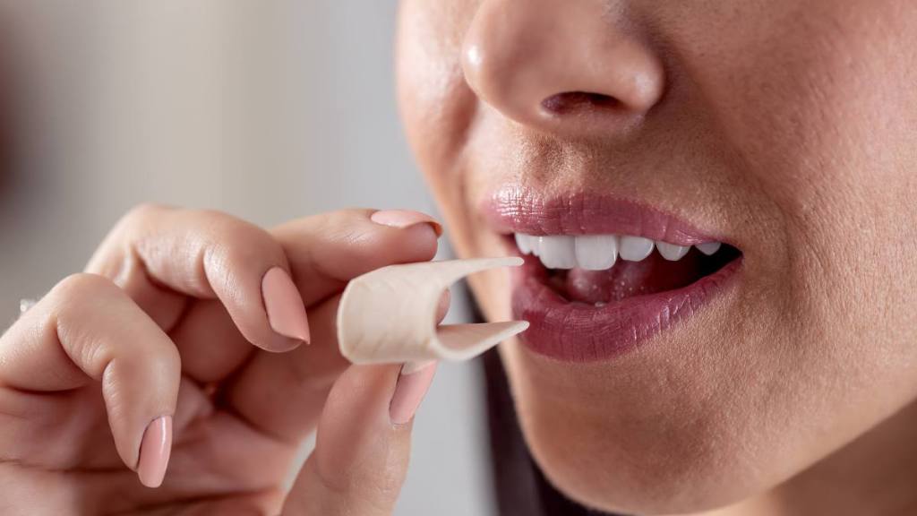 Detail of a woman putting a folded chewing gum into her mouth