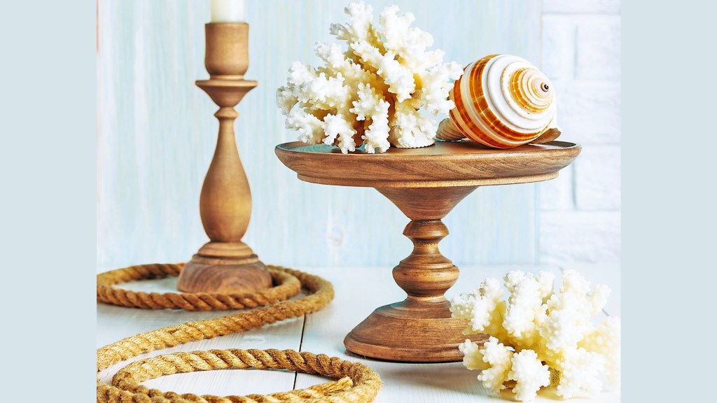 DIY beach decor: Still life with wooden cake stand topped with coral and a large shell alongside a candlestick, coral and a rope