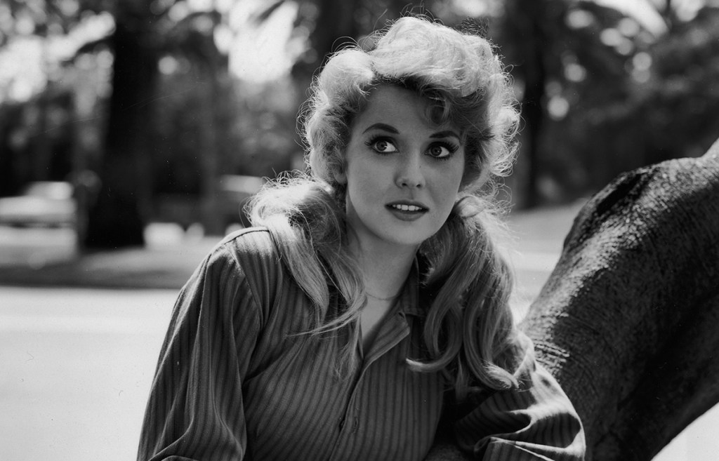 1962: Donna Douglas leans on a tree trunk in a promotional portrait for the television show 'The Beverly Hillbillies'