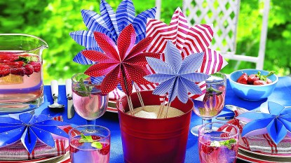 July Fourth Decor: July Fourth tablescape with centerpiece made by stacking DIY paper pinwheels in a sand-filled red pail