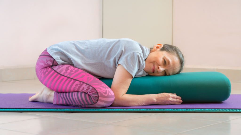Mature woman leaning on a prop, practicing restorative yoga