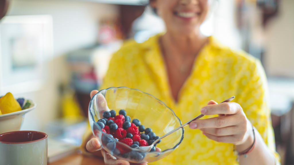 Woman eating a bowl of  blueberries and raspberries