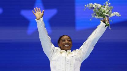 woman holding flowers up; simone biles olympics