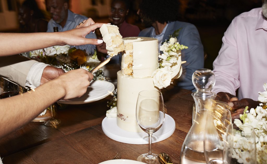 Hands cutting wedding cake