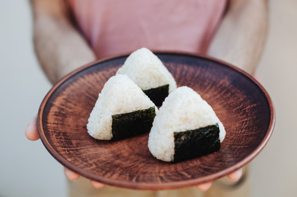 Woman holding a plate of onigiri rice balls from Japanese 7-Eleven