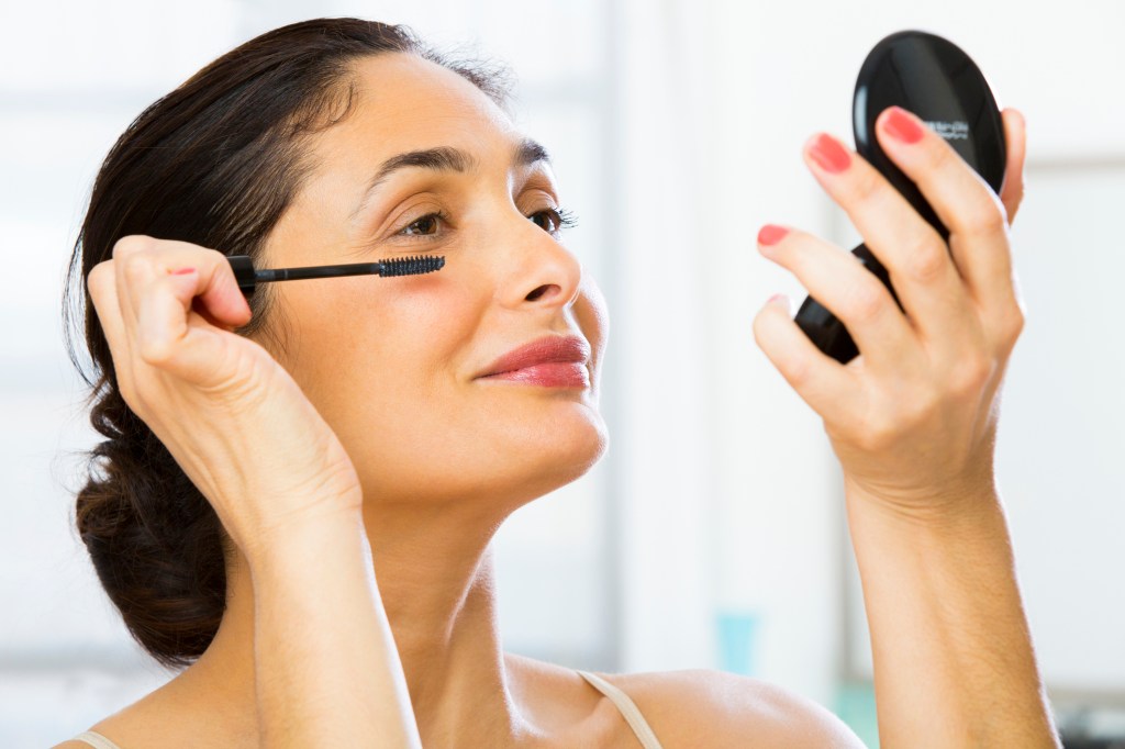 mature woman applying mascara to thin eyelashes